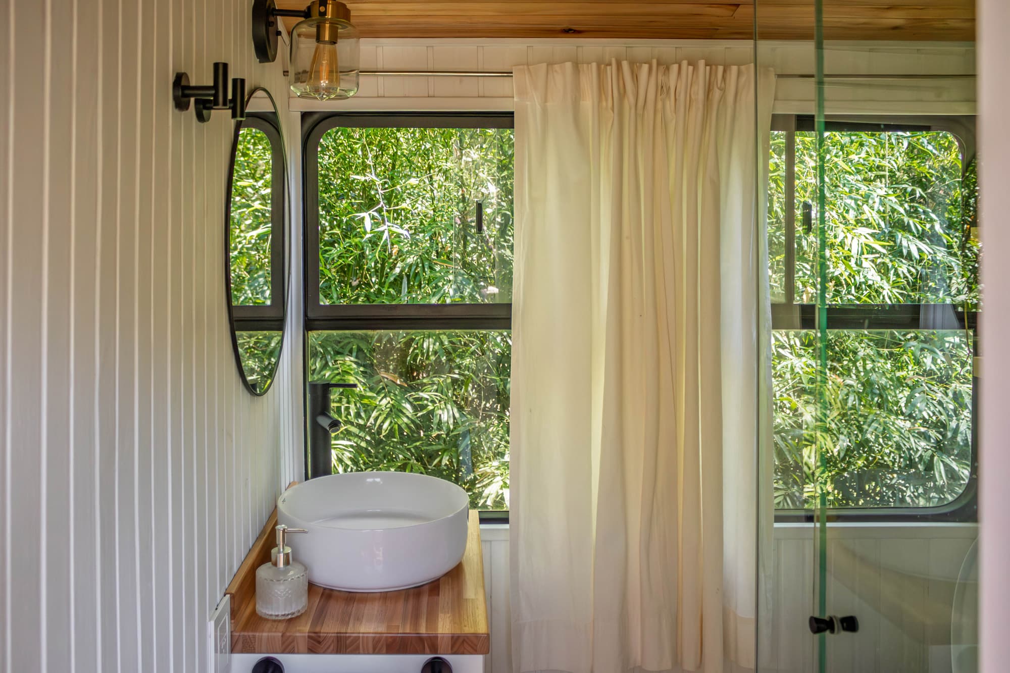 Baño del BondiHouse — lavabo artesanal con ventana oval al bosque nativo