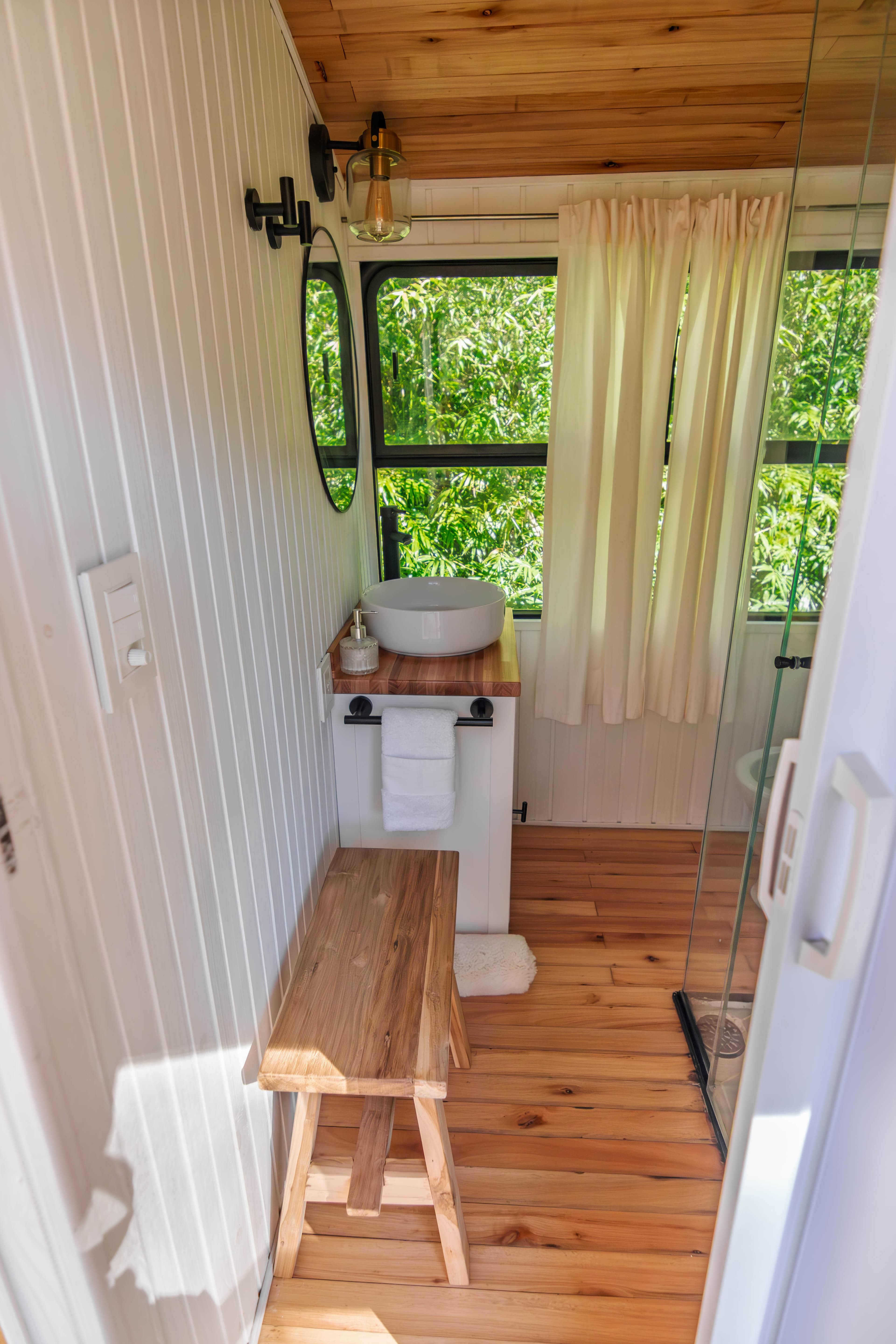 Detalles del baño de BondiHouse — ventana oval y terminaciones de madera