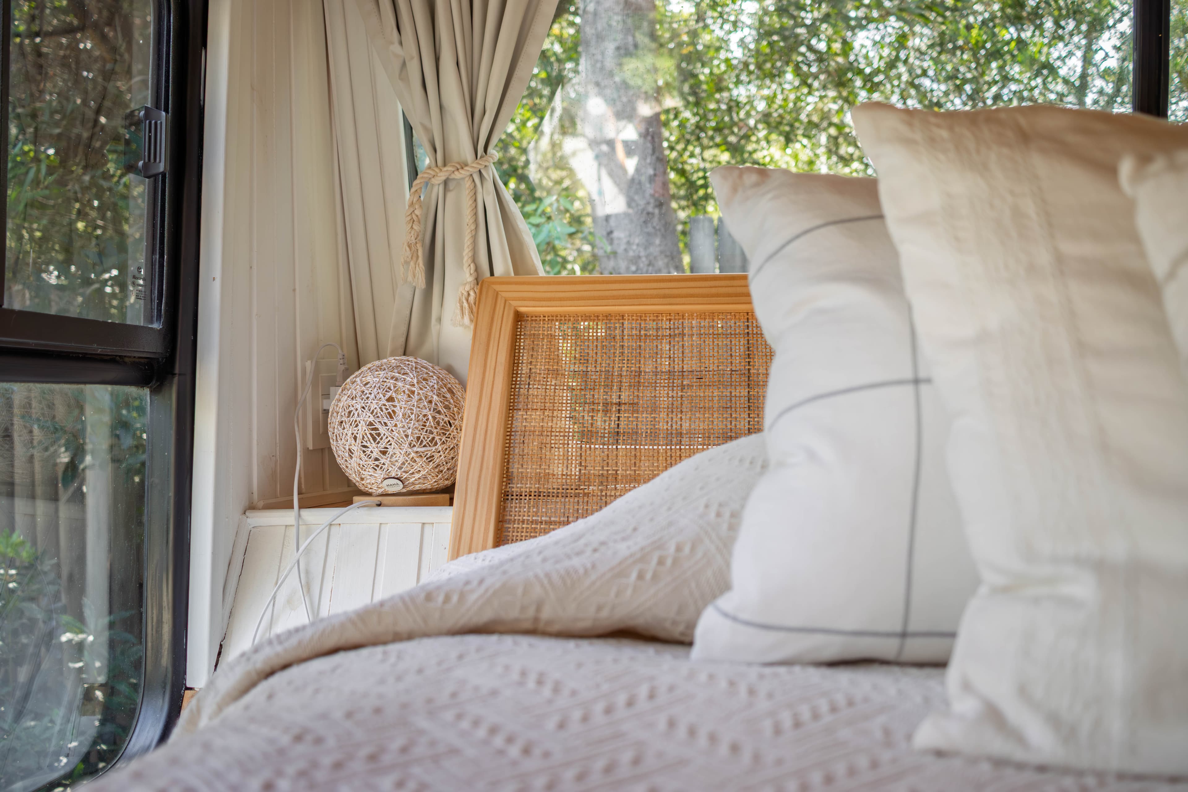 Cama king con ropa blanca en el dormitorio del ómnibus convertido en tiny house