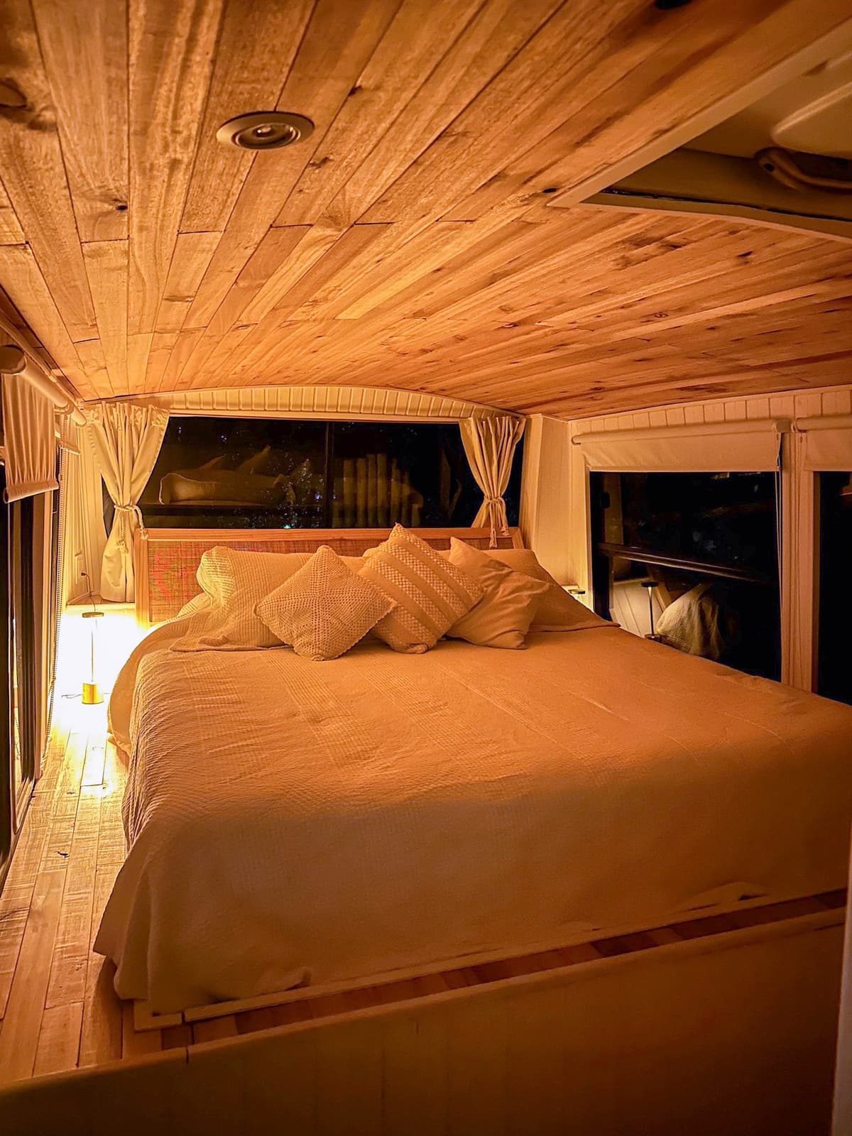 El dormitorio del Bondi de noche, con luz cálida y el techo curvo de madera