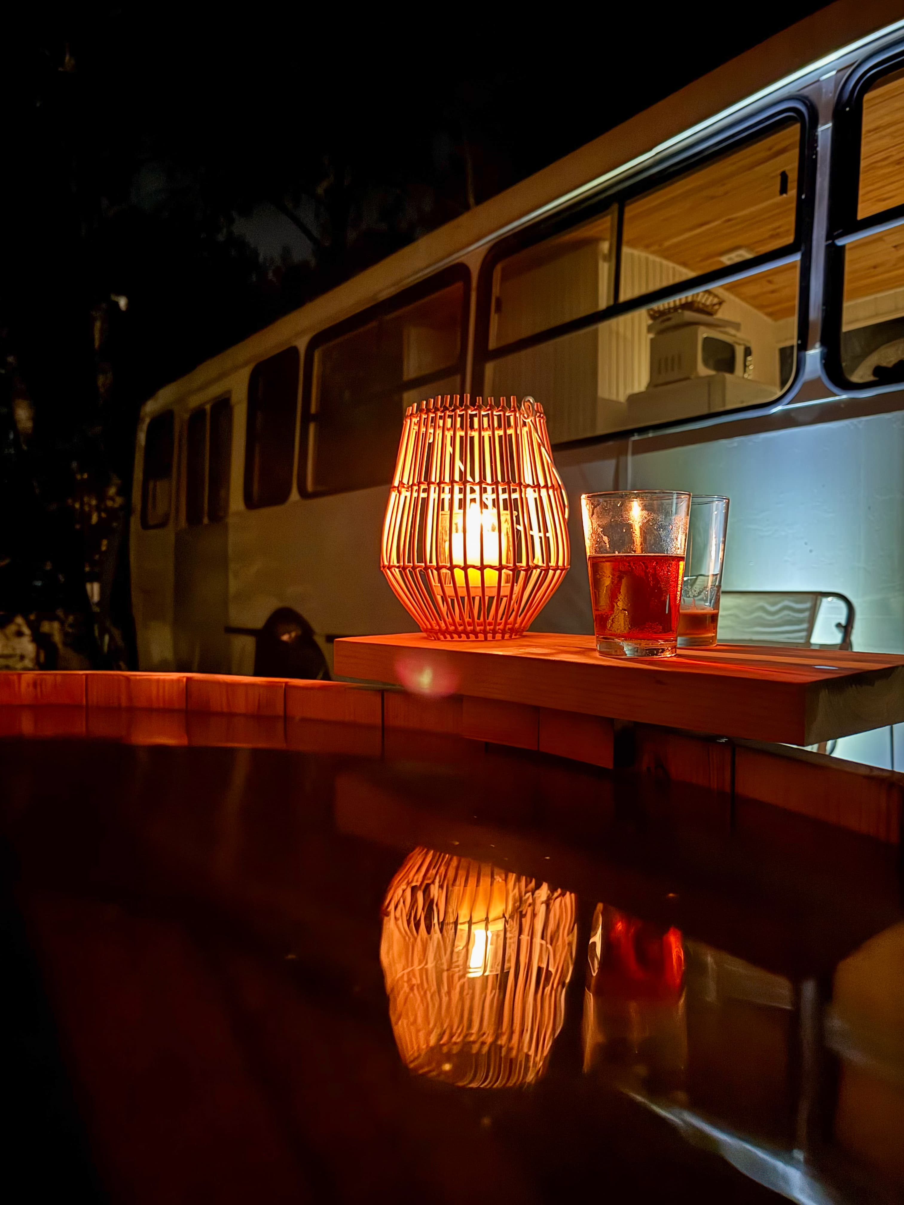 Vista nocturna de BondiHouse entre los árboles con luces suspendidas