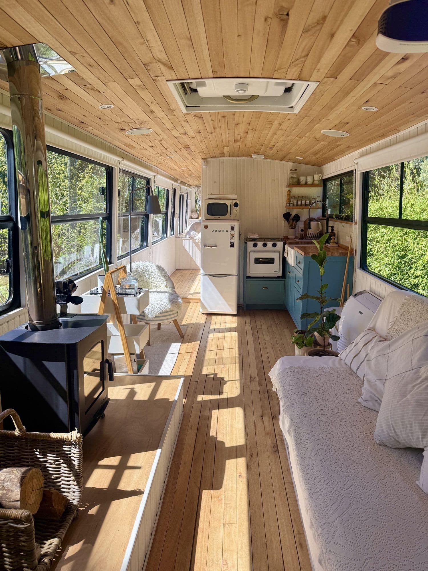Interior completo del Bondi: living con estufa a leña, cocina y techo de madera
