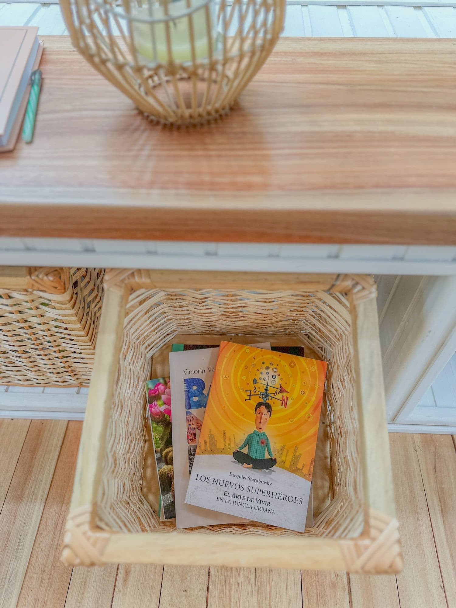 Libros en un canasto bajo el estante del living de BondiHouse