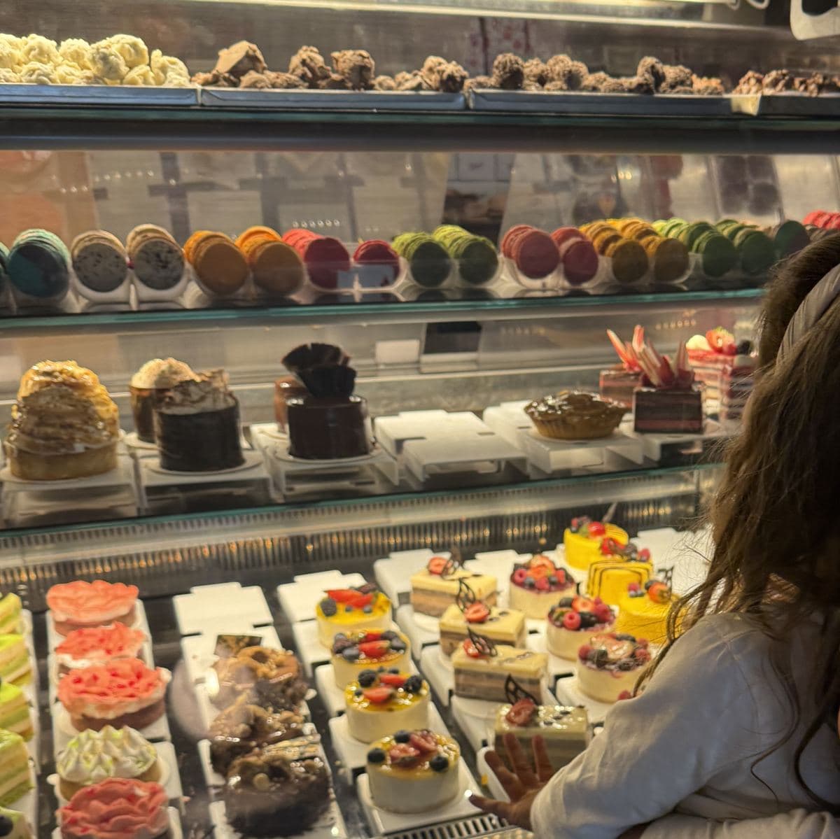 Franca frente a la vitrina de Baipa, llena de tortas, macarons y postres con frutos rojos