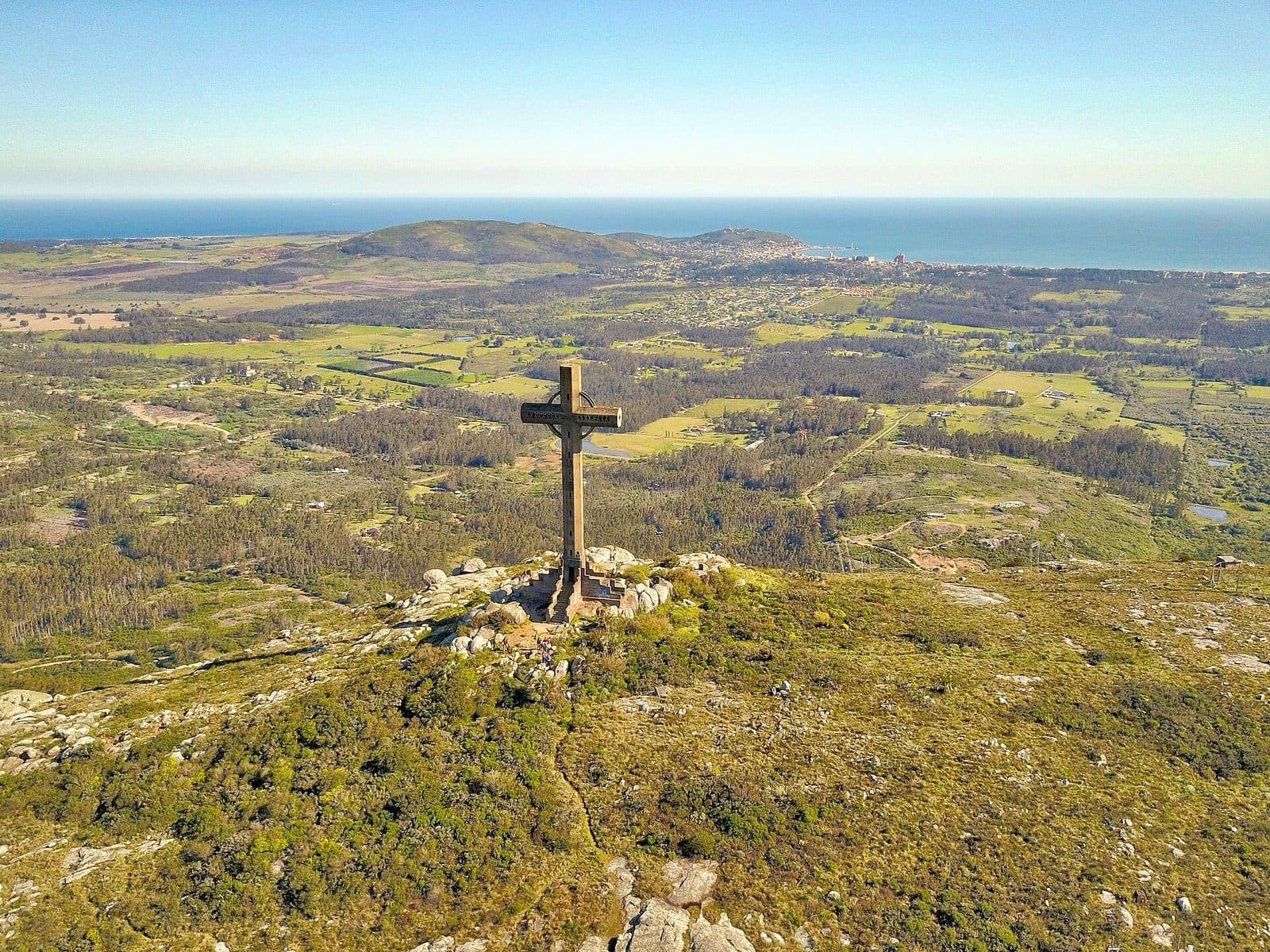 Cruz en la cima del Cerro Pan de Azúcar con el campo y el mar de fondo