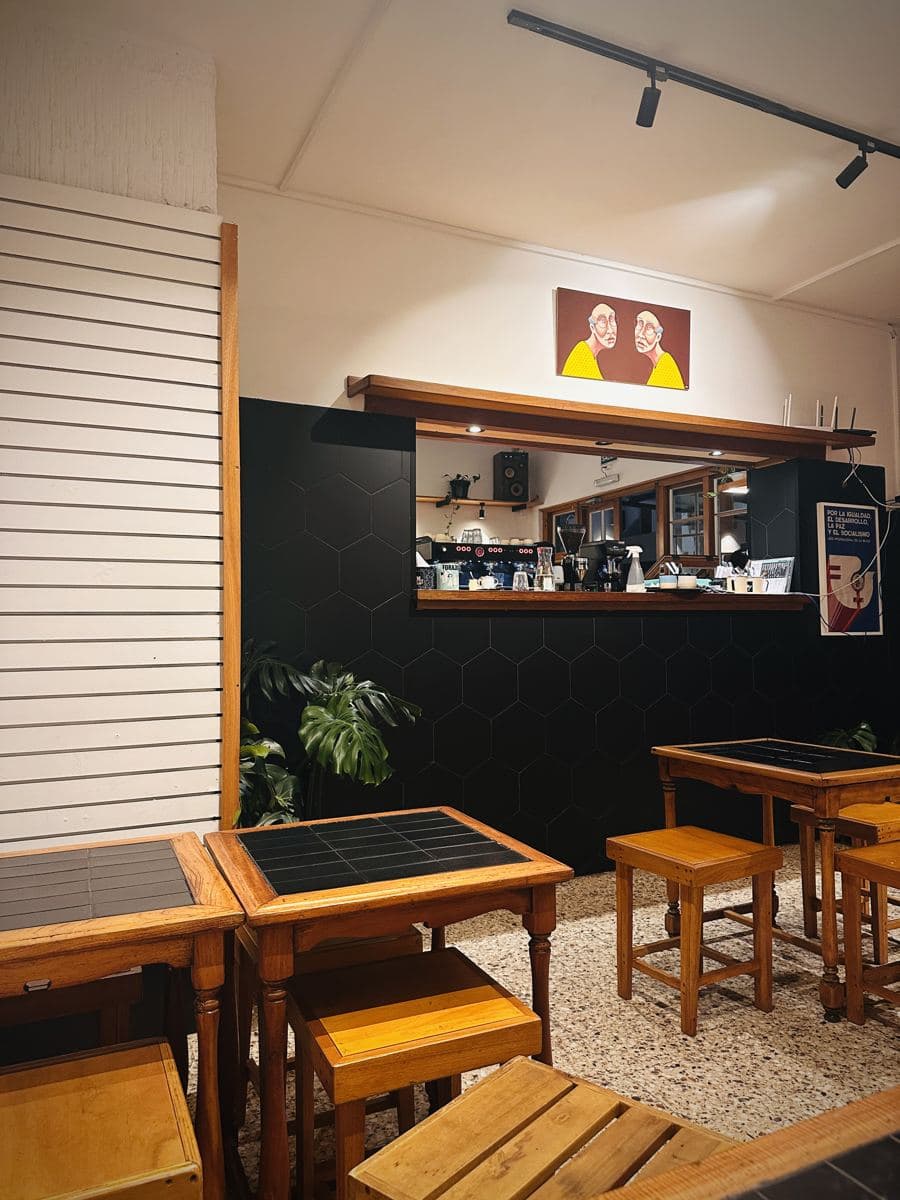 El salón de Forajida Café en Piriápolis: mesas de madera, la barra con la máquina de café y un cuadro en la pared