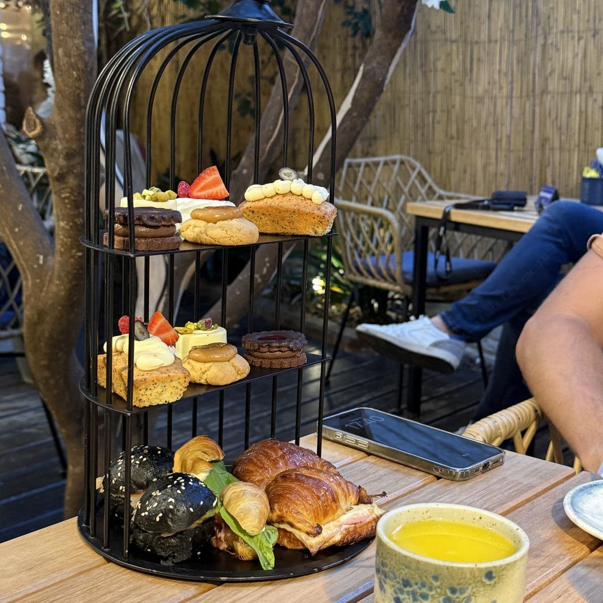 Merienda en Zunino Patisserie: una jaula de tres pisos con medialunas rellenas, alfajores y masas dulces, en el patio