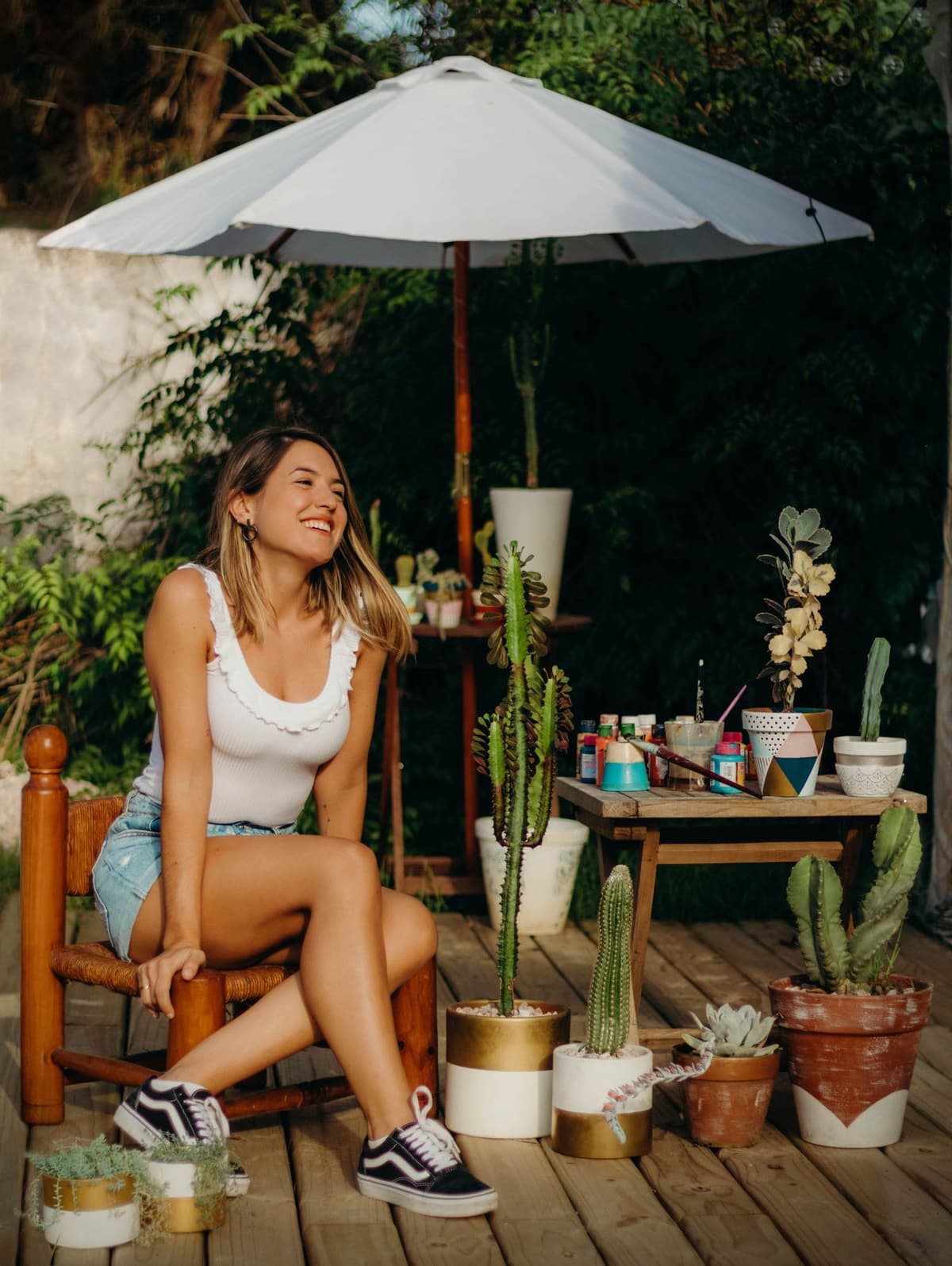 Agus sentada rodeada de sus macetas pintadas y cactus