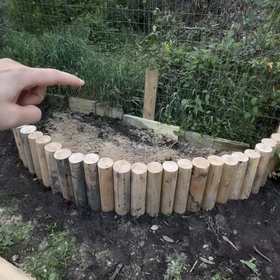 Mano señalando el primer nivel terminado, con tablas sueltas en la parte de atrás del cantero