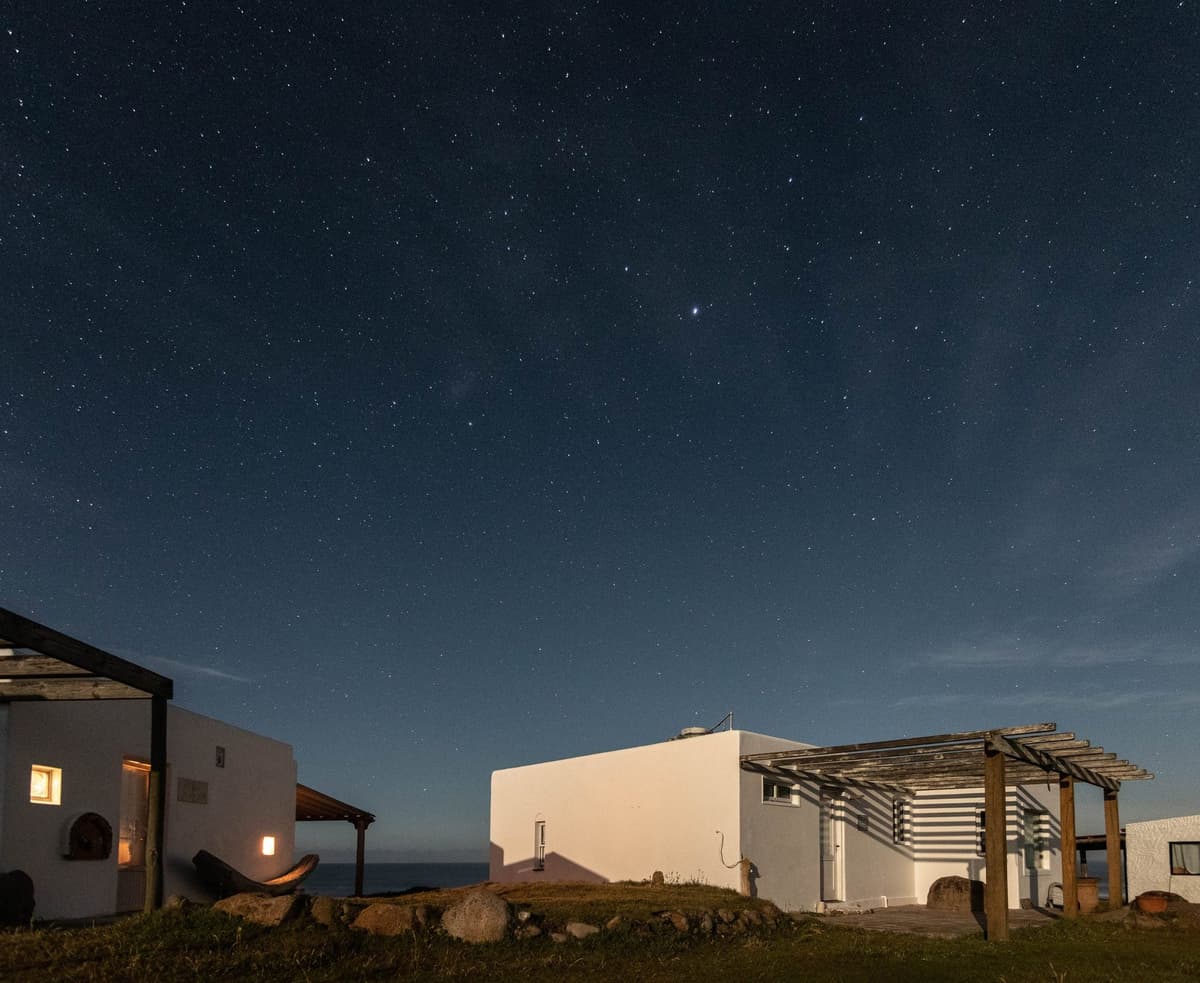 Casas blancas de Cabo Polonio iluminadas por la luz de la luna, bajo un cielo lleno de estrellas