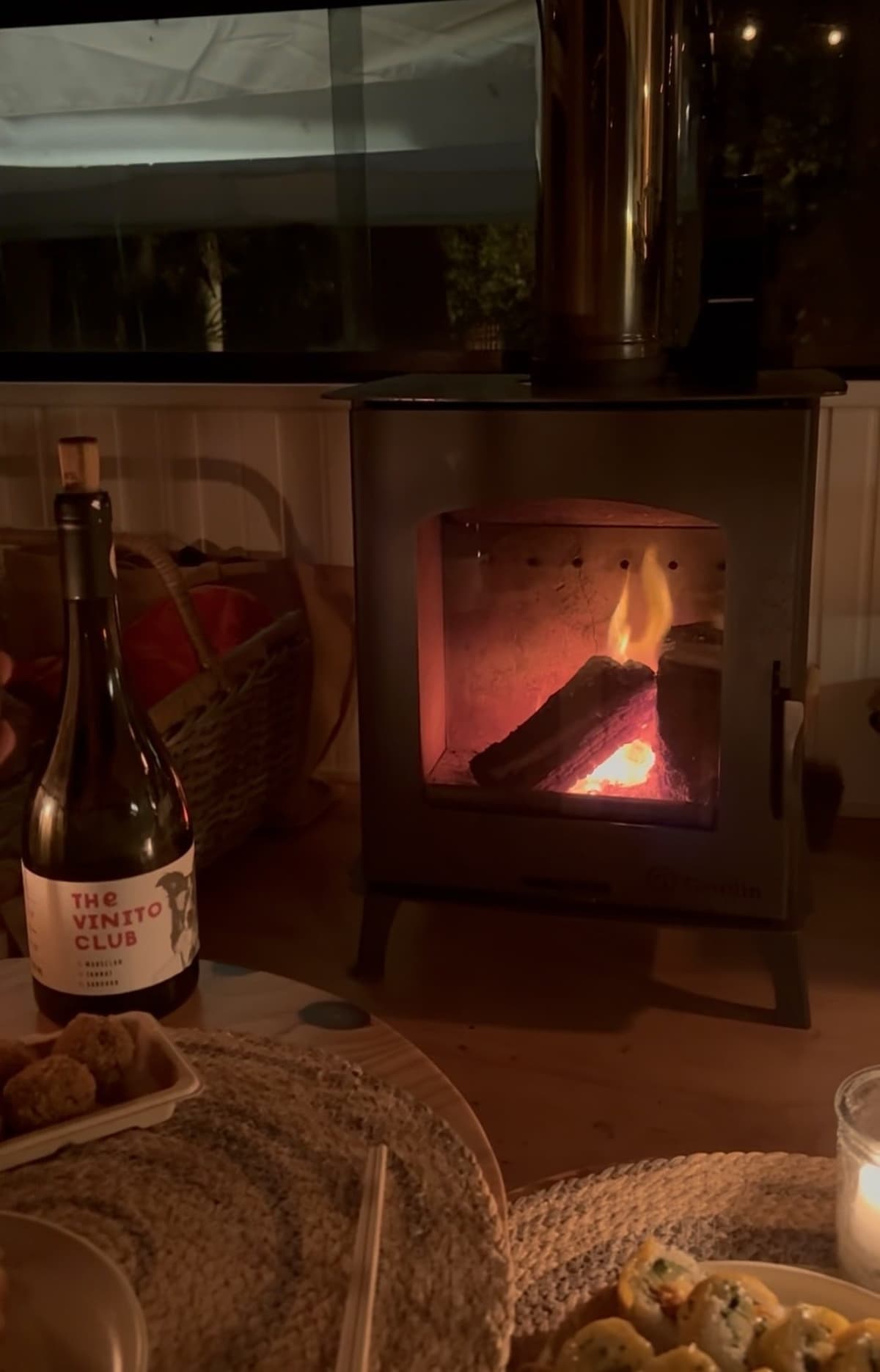 La estufa a leña encendida dentro del Bondi, con una botella de vino en la mesa