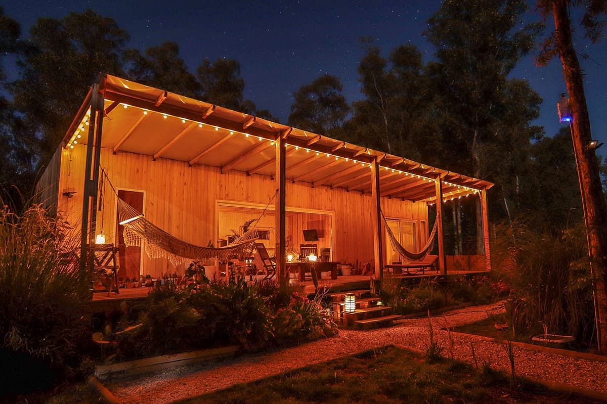 Nuestra casa de madera de noche, iluminada con luz cálida