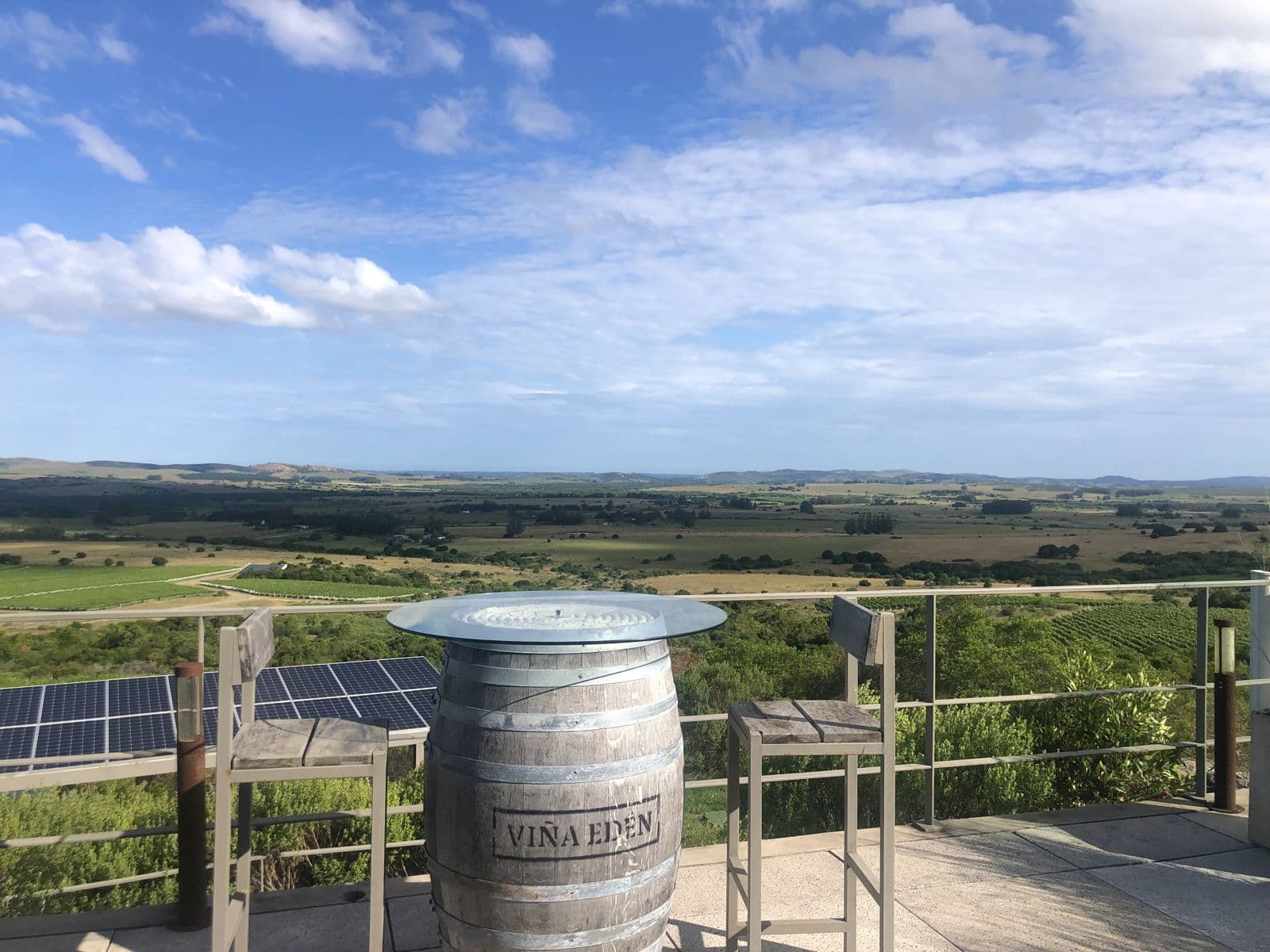Terraço da Viña Edén com um barril da vinícola como mesa e vista para os vinhedos e as serras de Pueblo Edén